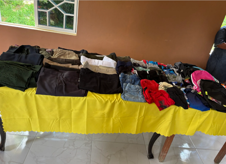 Table of folded donated clothing on a yellow tablecloth
